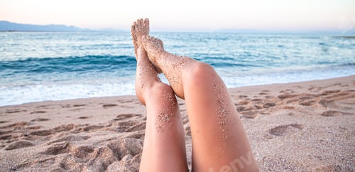 Preview: Legs of a woman relaxing on the beach by the sea.
