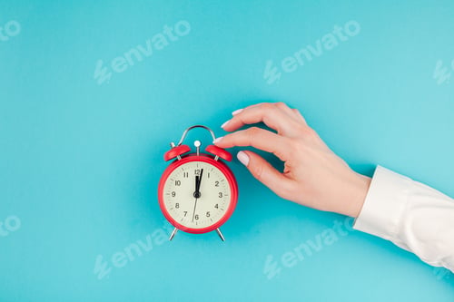 Preview: Woman hand holding the red vintage alarm clock