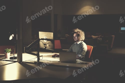 Preview: man working on computer in dark office