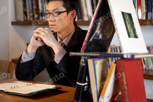 Preview: Young Man Looking Contemplative With A Small House Of Books