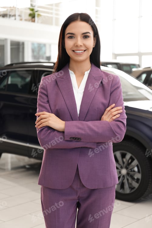Preview: Happy young saleswoman in modern car salon
