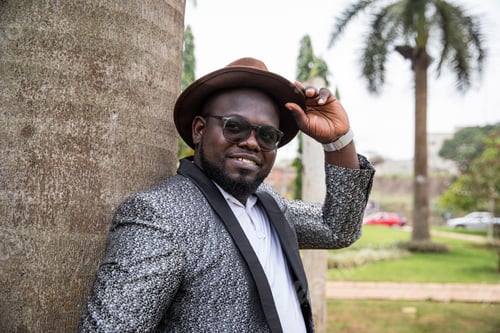 Preview: An elegantly dressed African gentleman smiles and holds his hat