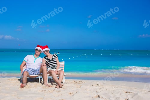 Preview: Young happy couple in red Santa hats on tropical beach