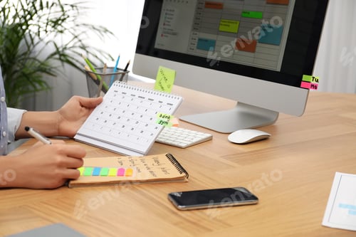 Preview: Woman making schedule using calendar at table in office, closeup