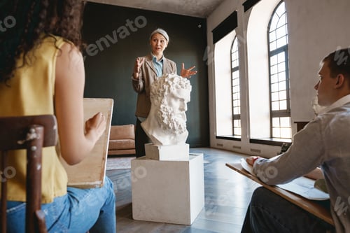 Preview: Mature teacher talking with her students during class in art school