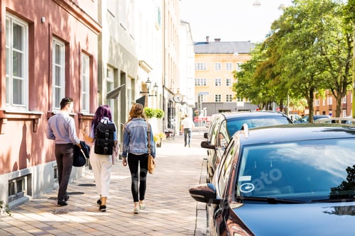 Preview: Rear view of friends walking on sidewalk in city