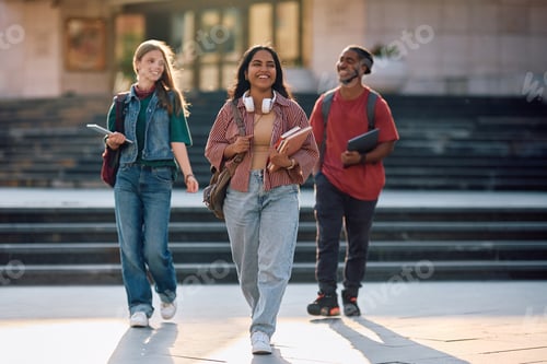 Preview: Multiracial group of happy students walking through university campus.