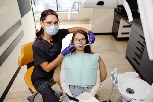Preview: Female dentist trying on a facial arch for a patient sitting in a dental chair