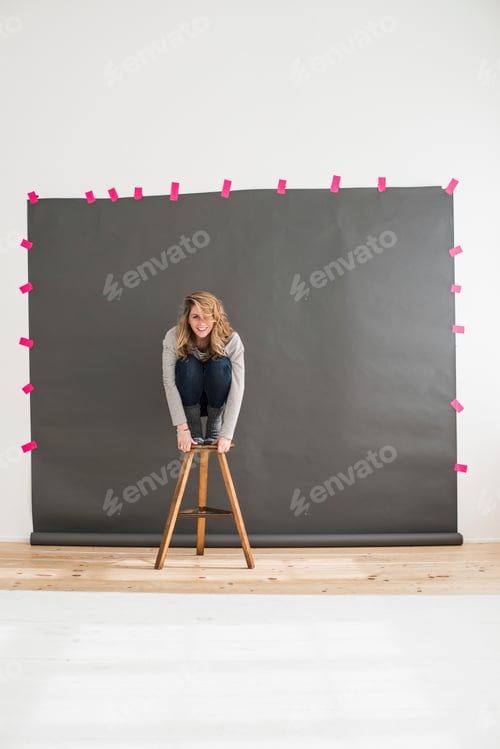 Preview: Mid adult woman crouching on top of stool