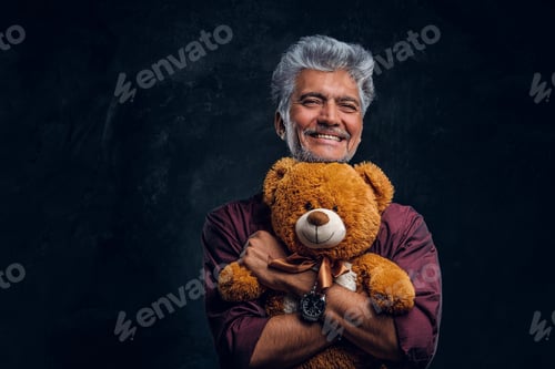 Preview: Joyful old man with teddy bear against dark background
