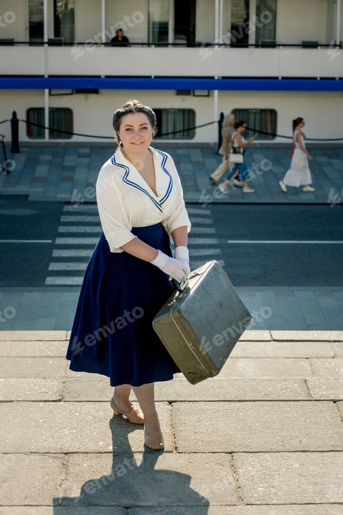 Preview: A girl stands with a suitcase in her hands on the embankment of the river station, port.