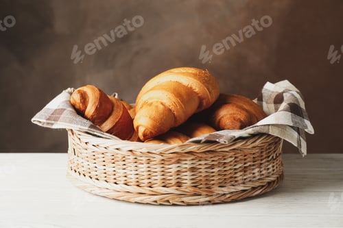 Preview: Wicker basket with croissants on wooden table, space for text