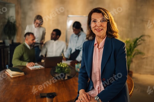 Visualização: Empresária madura confiante e sorridente olhando para a câmera durante a reunião