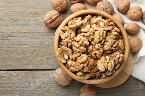 Preview: Peeled walnuts in bowl and whole ones on wooden table, flat lay. Space for text