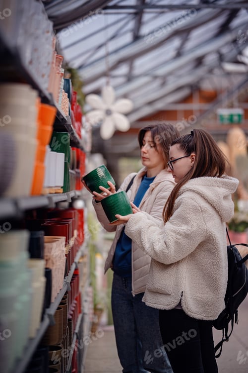 Preview: Women Choosing Ceramic Planters in Garden Store Aisle