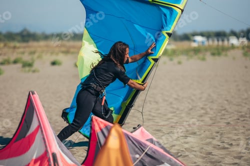 Preview: Young sporty woman preparing her kite for kitesurfing