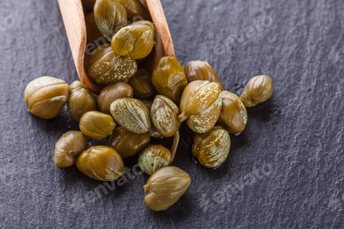 Preview: pickled capers on a dark stone background