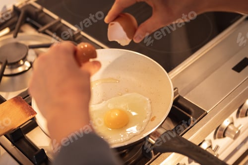Preview: Mid section of woman cooking eggs in the kitchen