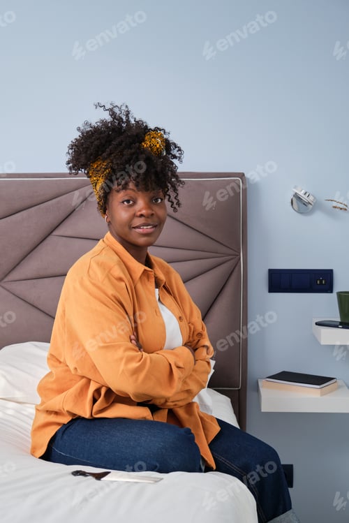 Preview: Portrait of african woman looking at camera in her bedroom.