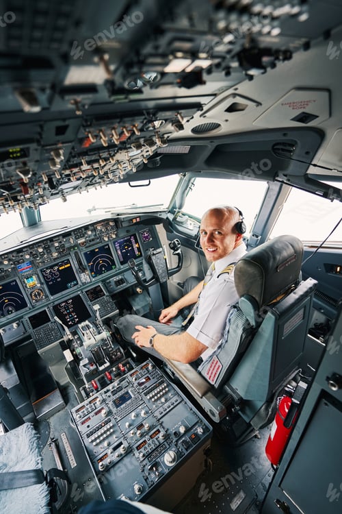 Preview: Pleased young pilot sitting in the cockpit before the take-off