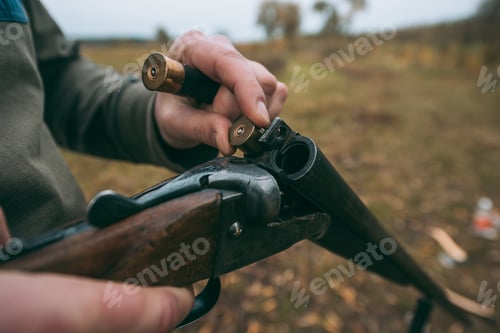 Preview: Cropped image of hunter loading a gun with bullets