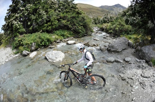 Preview: Woman pushing mountain bike through water, New Zealand