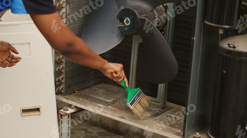 Preview: Mechanic sweeping debris in HVAC unit
