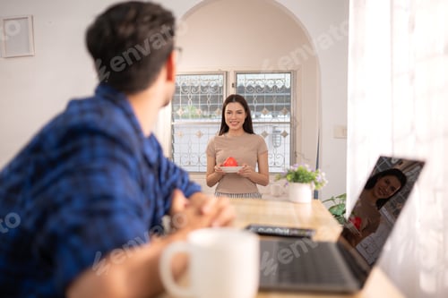 Preview: Portrait of a young freelancer smiling while working online via laptop at home with his girlfriend