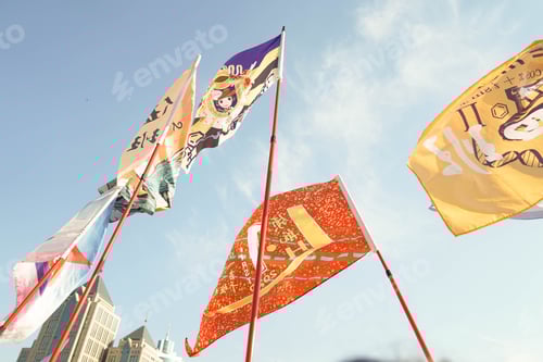 Preview: Series of flags of different colors hang on poles in front of a white building