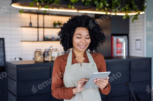 Preview: Young African American woman wearing an apron working in a restaurant and eating place, standing