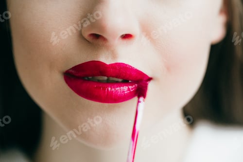Preview: Closeup shot of female paint her lips by cosmetic brush red lipstick on lips