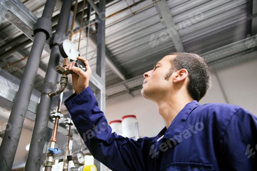 Preview: Technician working in a technical room looking at gauge
