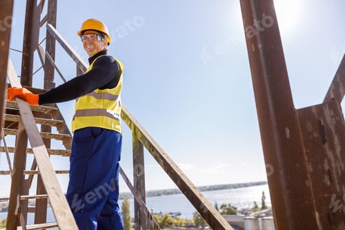 Preview: Cheerful male engineer standing on stairs outdoors