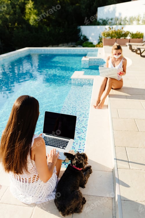 Preview: women using laptop work on social distance wearing protective face masks