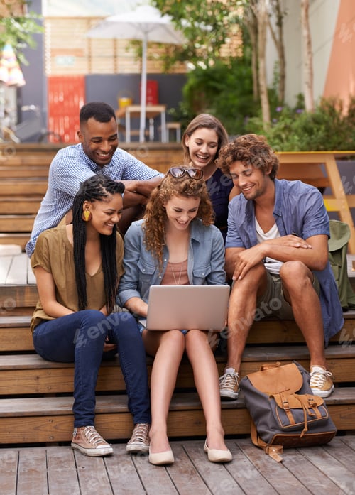 Preview: Lets take this lesson online. A group of students gathered around a laptop outdoors.