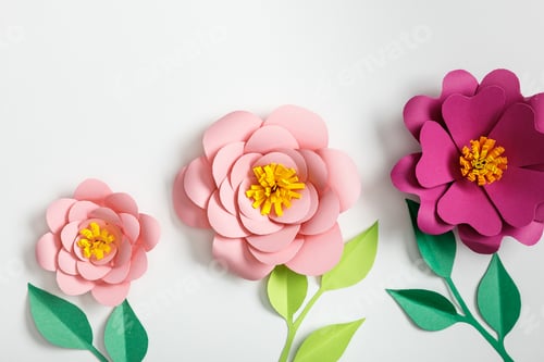 Preview: top view of pink paper flowers and green plants with leaves on grey background