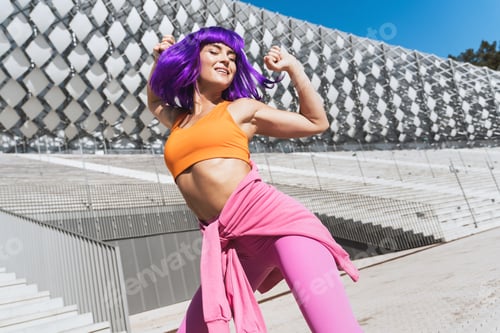 Preview: Carefree active woman dancer wearing colorful sportswear having fun on the street