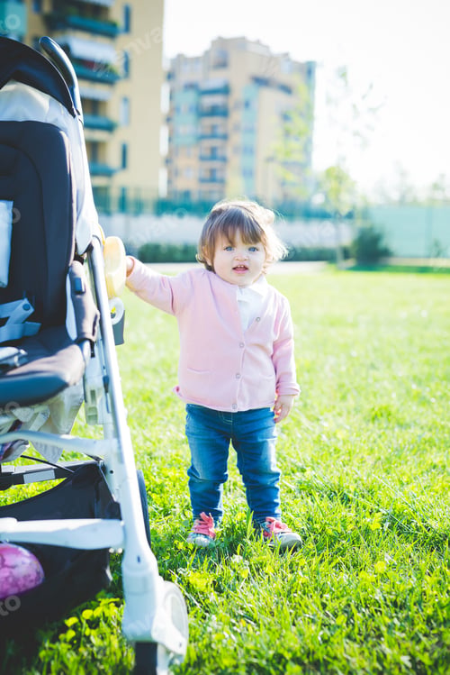 Preview: Female toddler holding onto pushchair in park