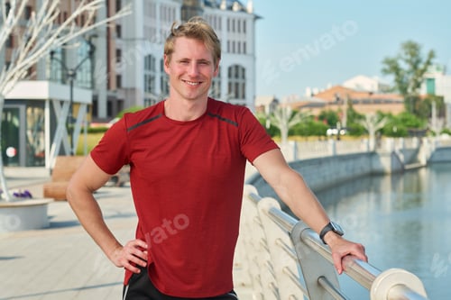 Preview: Portrait of Young Man Smiling Outdoors near Urban Riverfront