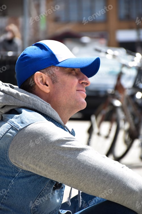 Preview: Portrait of middle aged man sitting on a curb looking up