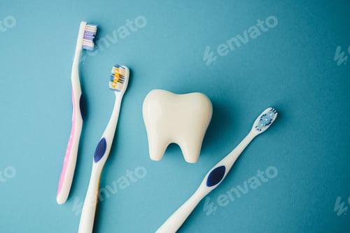 Preview: Dental care. White tooth shape next to three colorful toothbrushes on blue background.