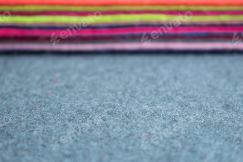 Preview: Pile of felt flaps blurred background. Defocus Stack of colorful felt flaps on a gray fabric