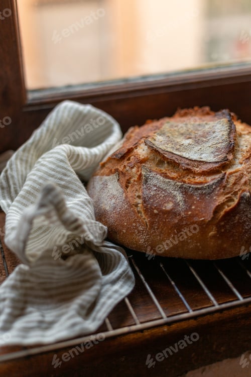 Preview: A loaf of freshly baked sourdough bread near a linen stripy towel
