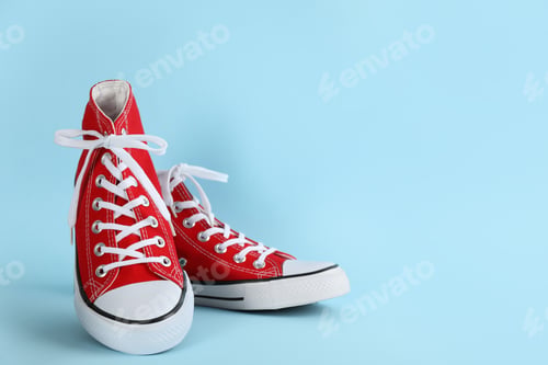 Preview: Pair of stylish sneakers on light blue background, space for text