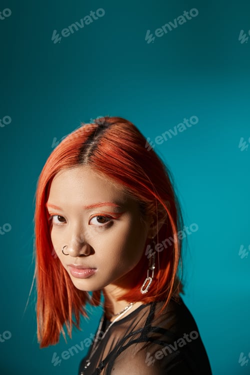 Preview: portrait of mesmerizing asian woman with bold eye makeup looking at camera on blue background