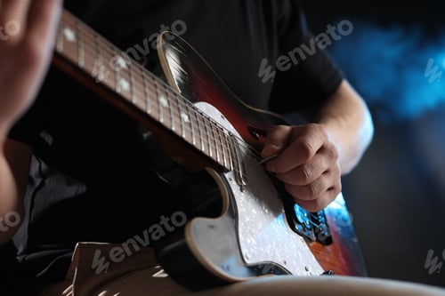 Preview: Man playing guitar on dark background with smoke, closeup