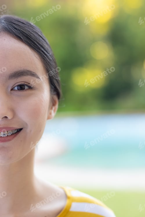 Preview: Smiling young young asian woman with braces enjoying outdoor time near swimming pool, copy space