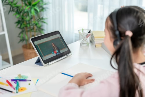 Preview: Rear view of young student learning online class with teacher at home.