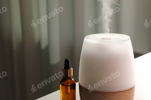 Preview: Modern aroma lamp and bottle of essential oil on table indoors, closeup