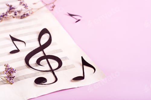 Preview: Paper musical clef and paper notes on a sheet of music and dry flowers.